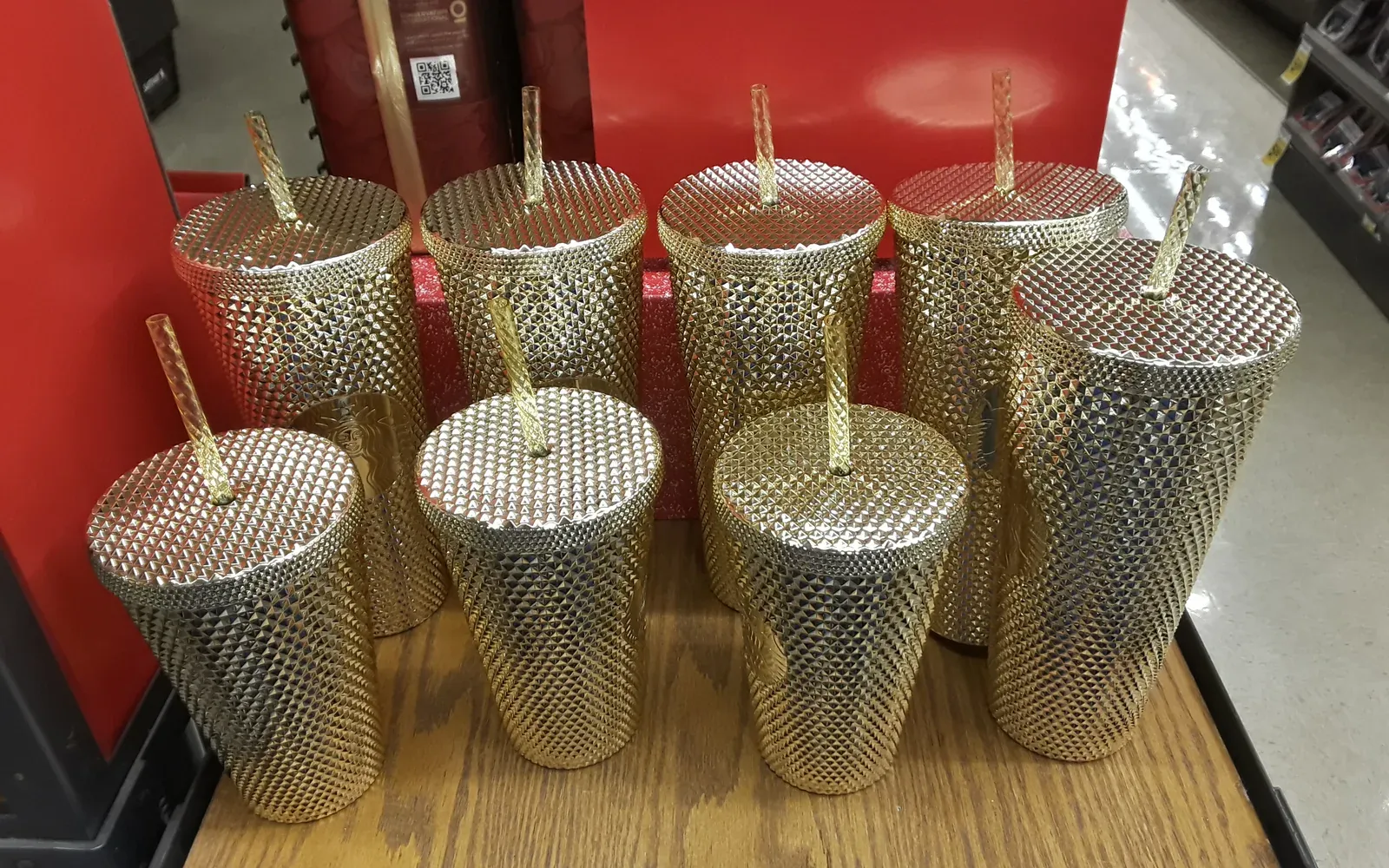 Mehrere goldene Starbucks Cold Cups mit Strohhalm und geprägtem Deckel im Verkaufsregal