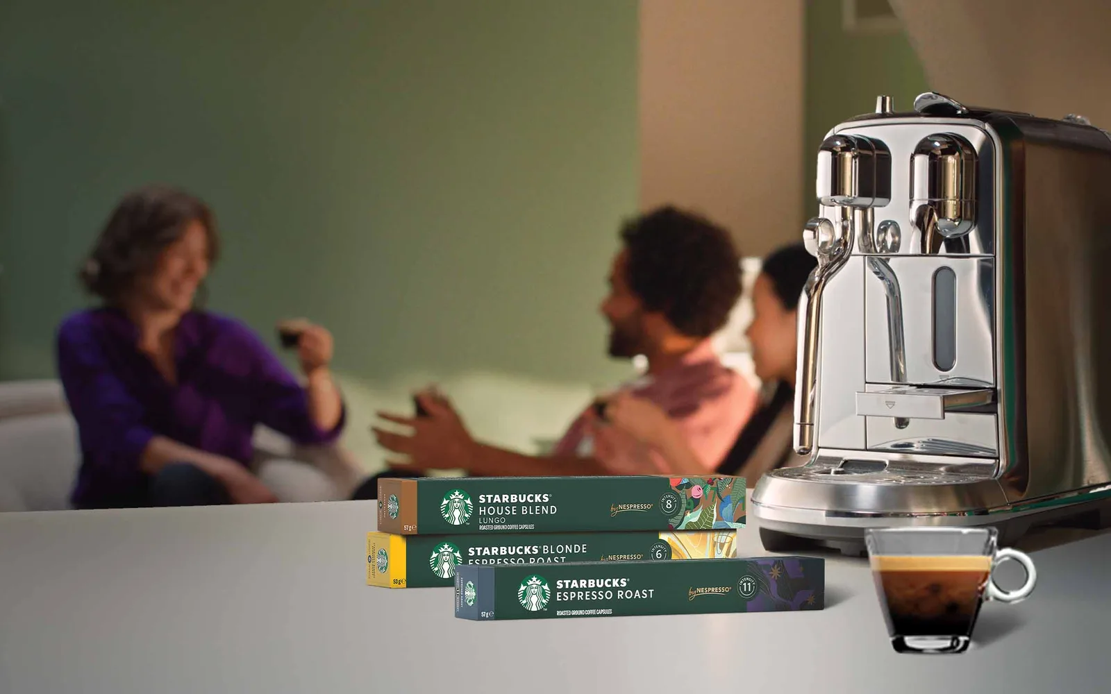 Drei Packungen Starbucks by Nespresso Kapseln neben einer Kapselmaschine und einer Tasse Espresso
