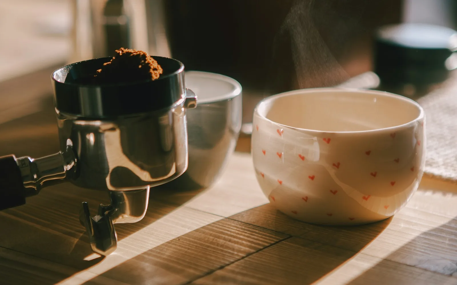Frisch gemahlener Kaffee und eine dampfende Tasse im Morgenlicht
