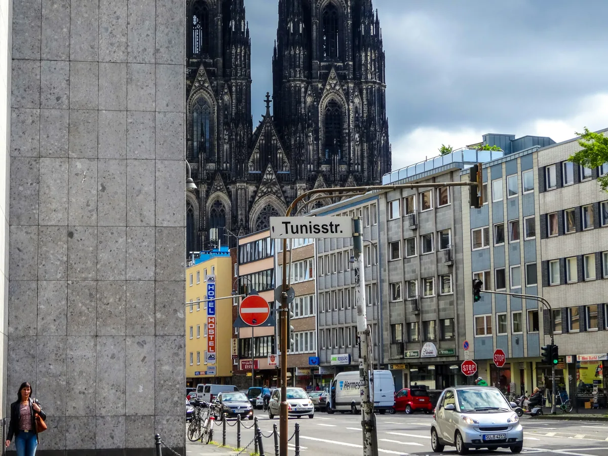 Kölner Dom über einer Straßenkreuzung mit Straßenschild Tunisstr.