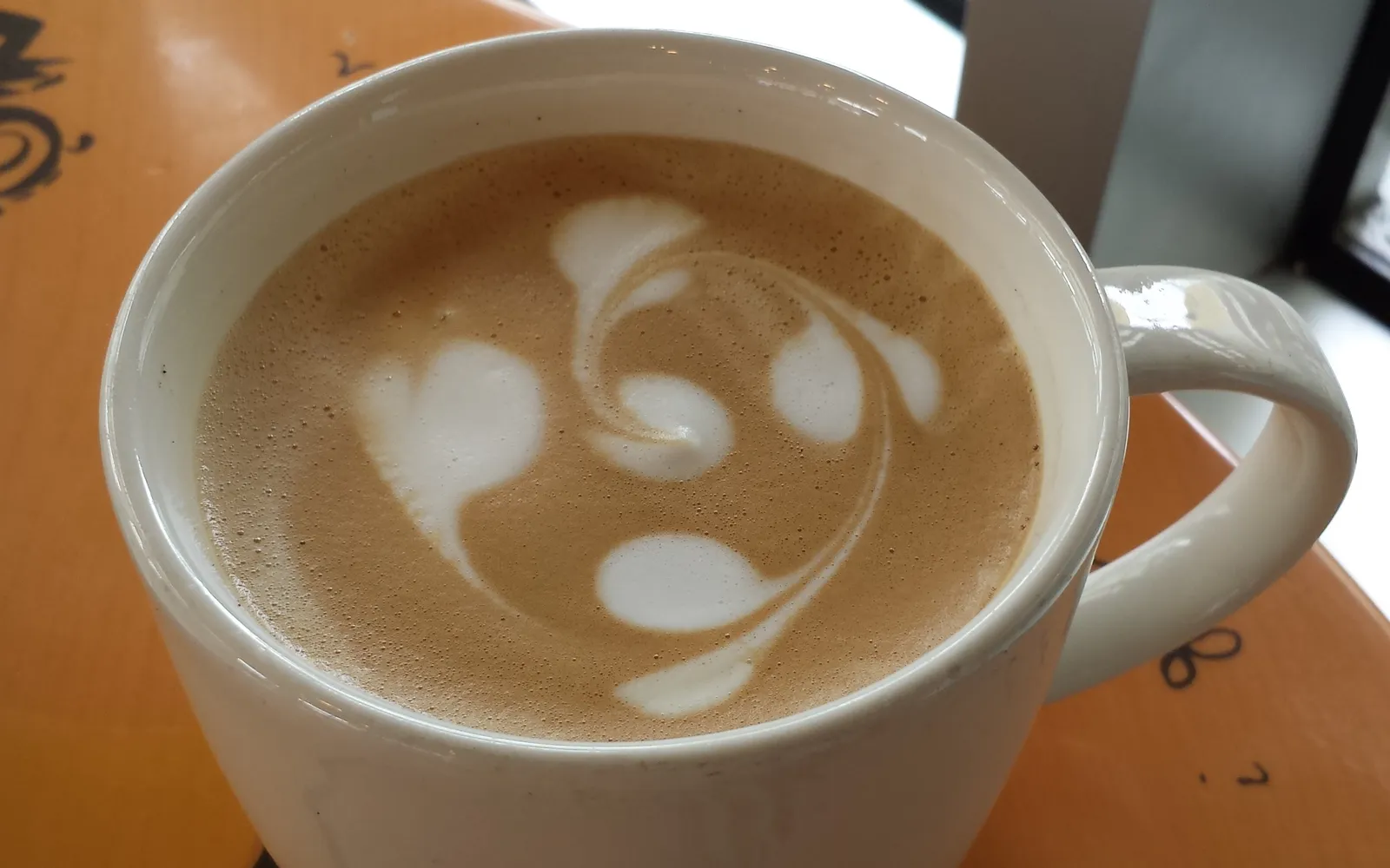 Caffè Latte mit Latte-Art in weißer Tasse, fotografiert in einer Starbucks-Filiale