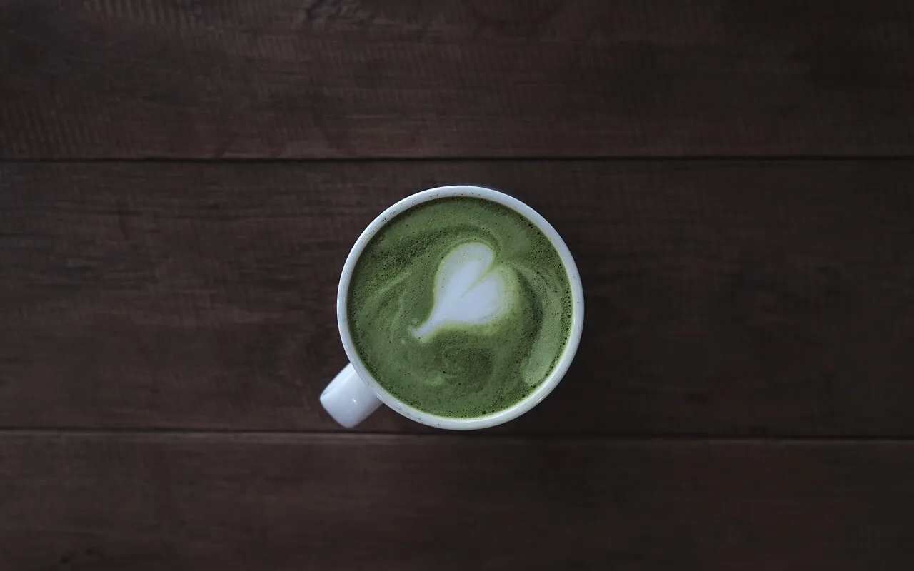 Matcha Latte mit Herz aus Milchschaum in weißer Tasse von oben