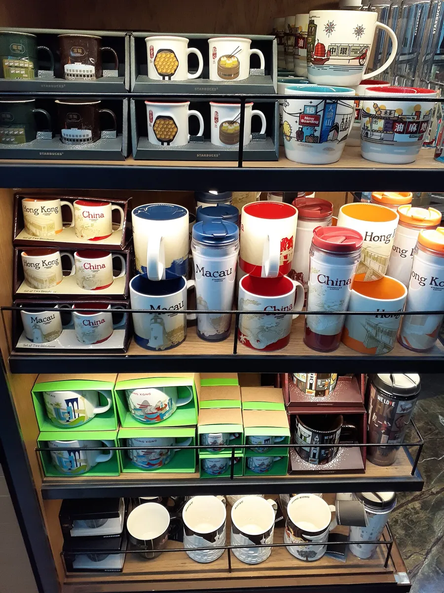 Starbucks-Merchandise-Regal mit Städtetassen, Tumblern und Thermobechern in einer Filiale