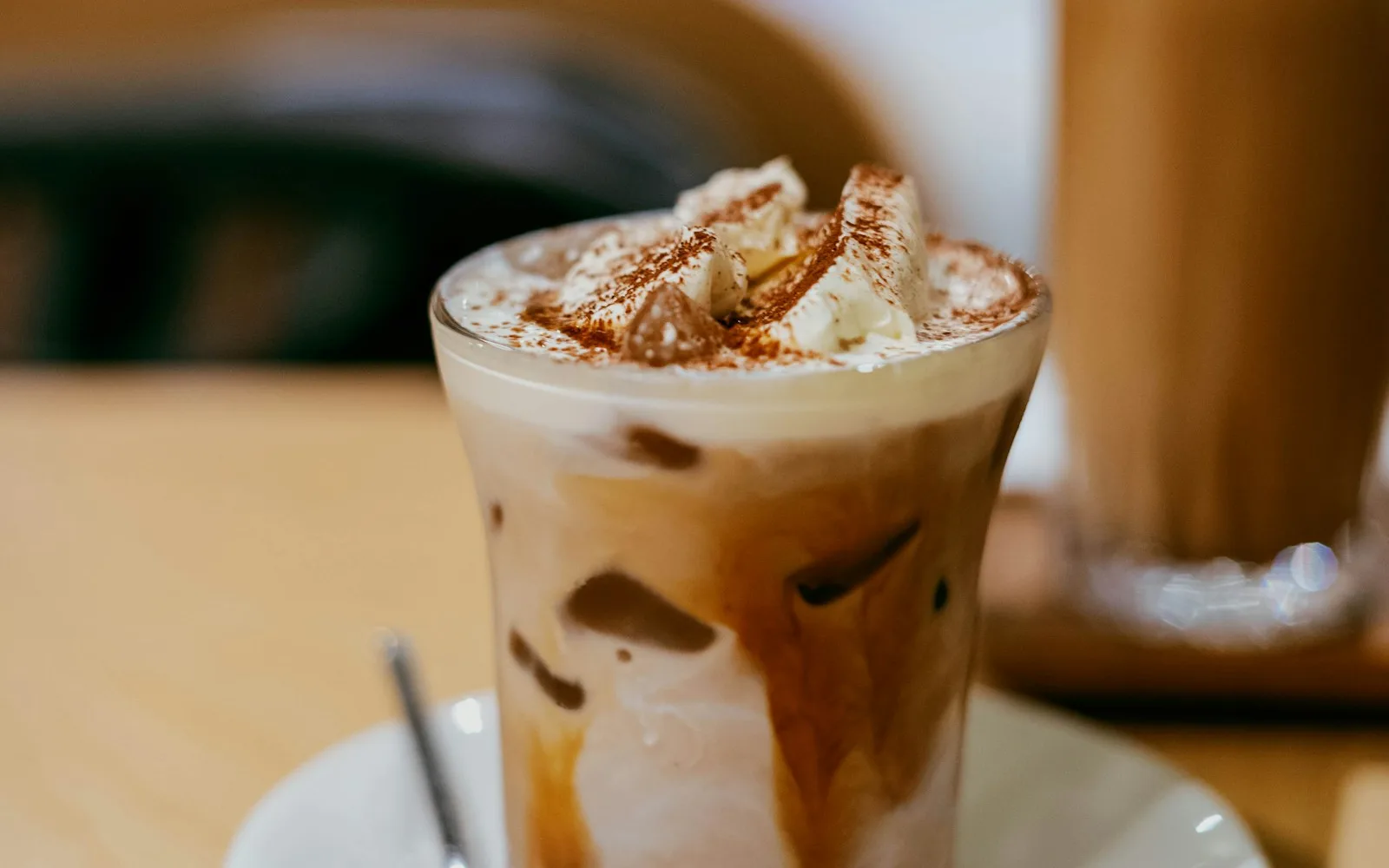 Mocha mit Sahnehaube und Kakaopulver im Glas auf einer Untertasse