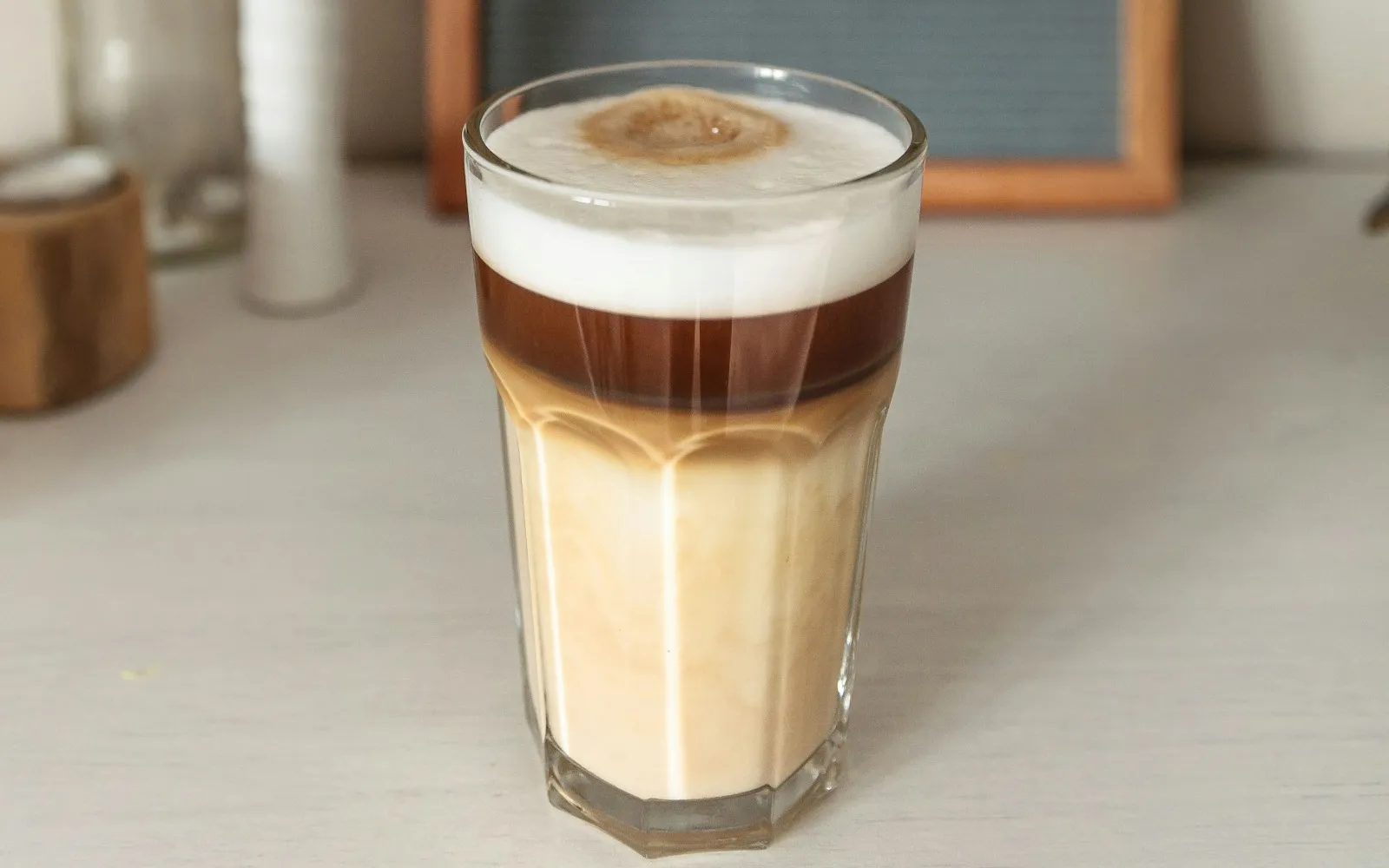 Geschichteter Latte im hohen Glas auf einem hellen Tisch