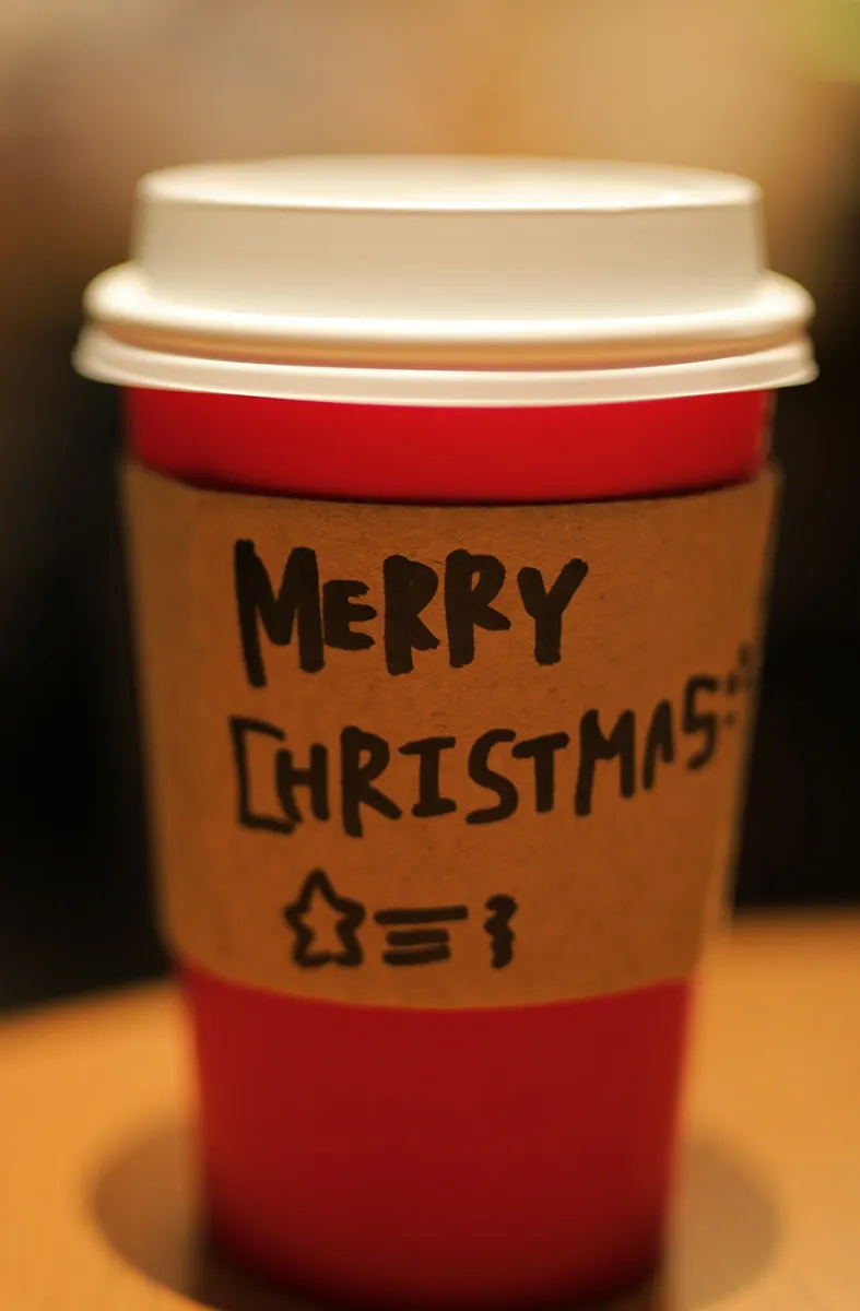 Roter Starbucks Holiday-Becher mit Papphülle und handgeschriebenem Merry Christmas